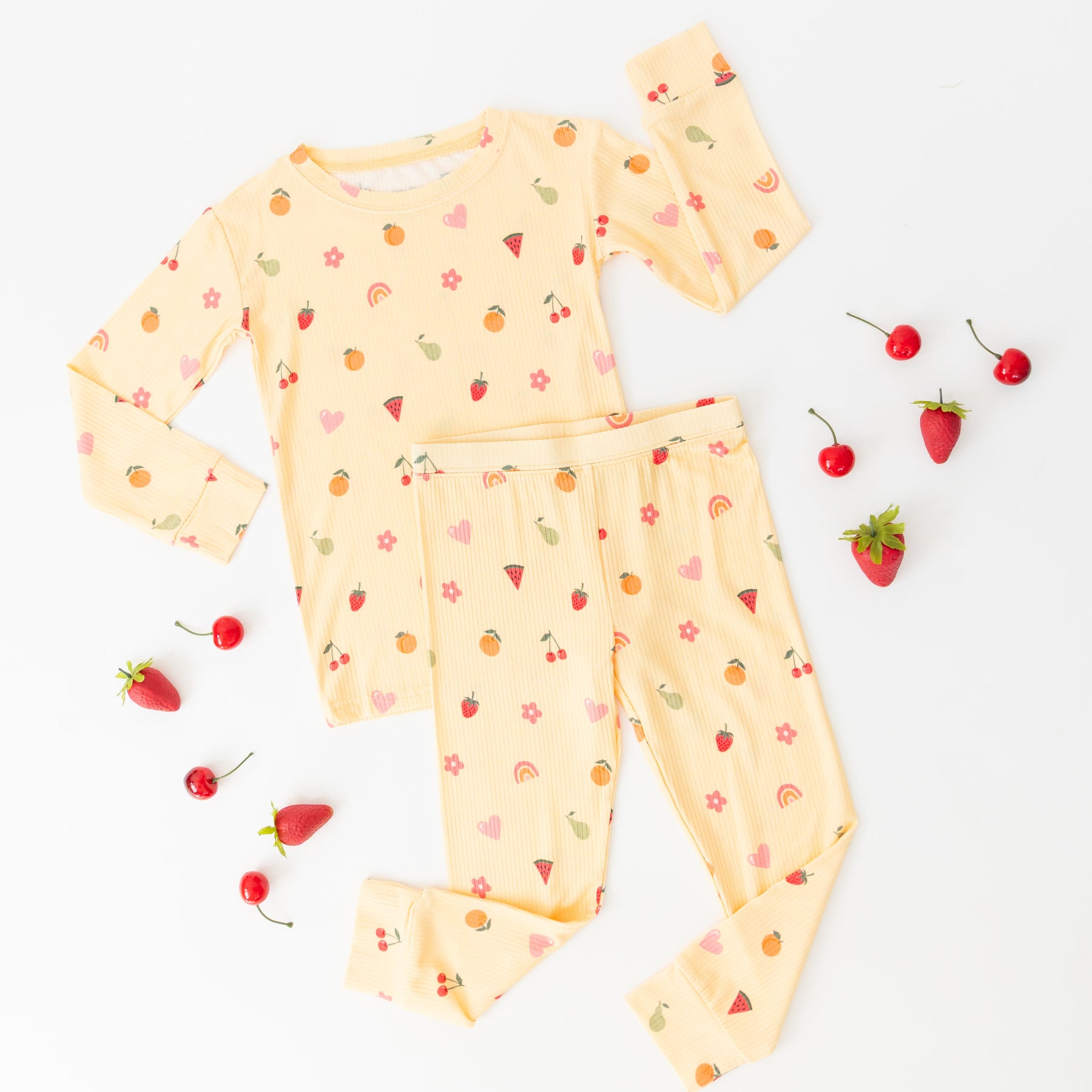 Yellow children's pajama set with fruit pattern on a white background