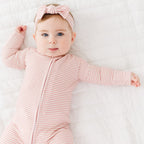 Baby wearing a pink and white striped outfit with a matching headband on a white background