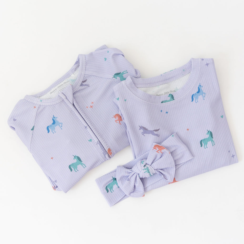 Baby outfit set with light purple ribbed fabric, including a onesie and headband with unicorn pattern on a white background.