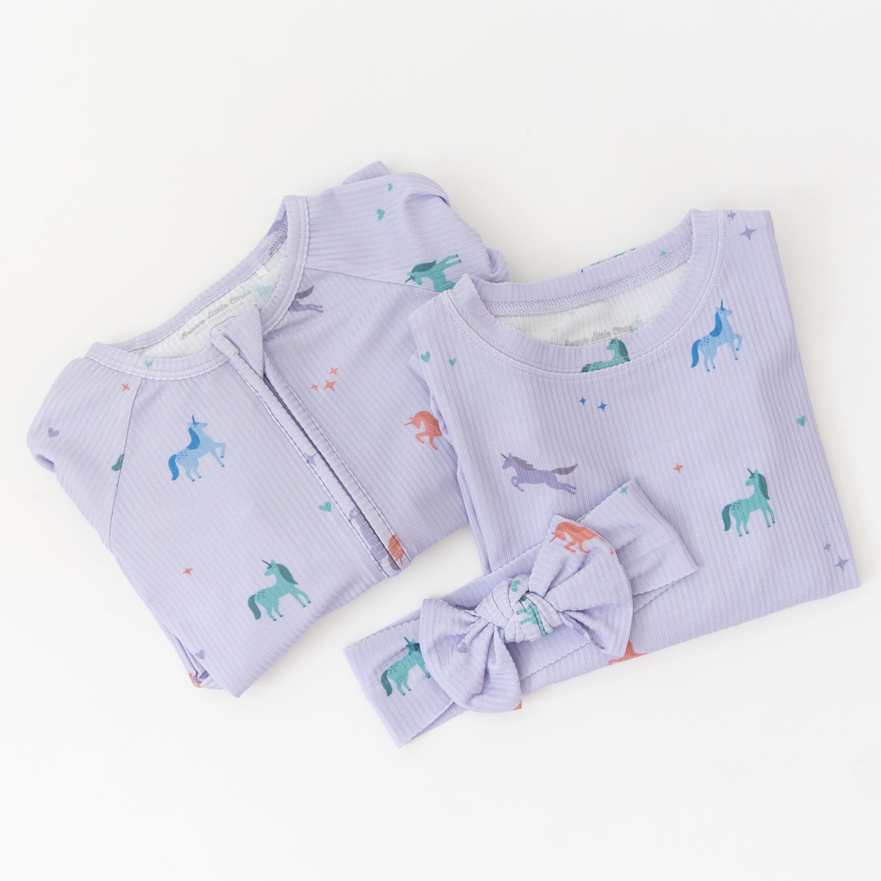 Baby outfit set with light purple ribbed fabric, including a onesie and headband with unicorn pattern on a white background.