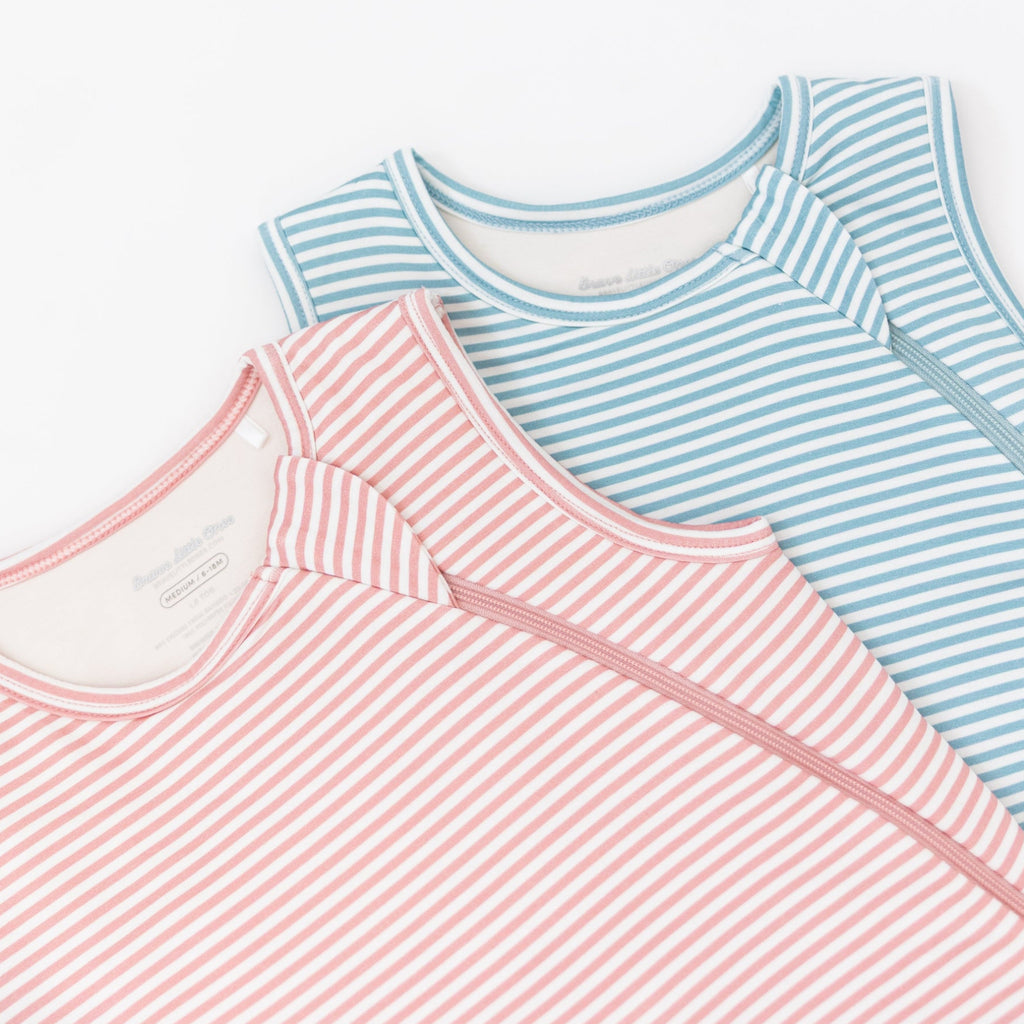 Two striped sleeping bags, one blue and white, one pink and white, on a white background
