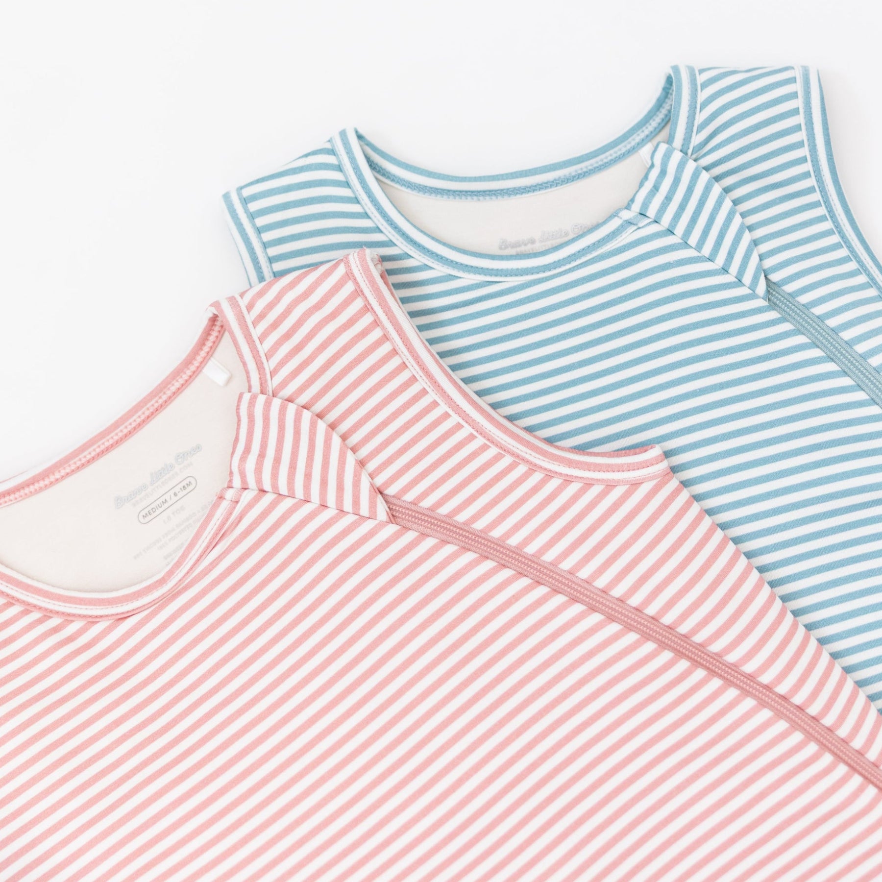 Two striped sleeping bags, one blue and white, one pink and white, on a white background