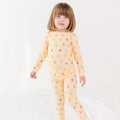 Child wearing a yellow pajama set with heart patterns on a white background