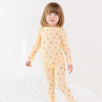 Child wearing a yellow pajama set with heart patterns on a white background