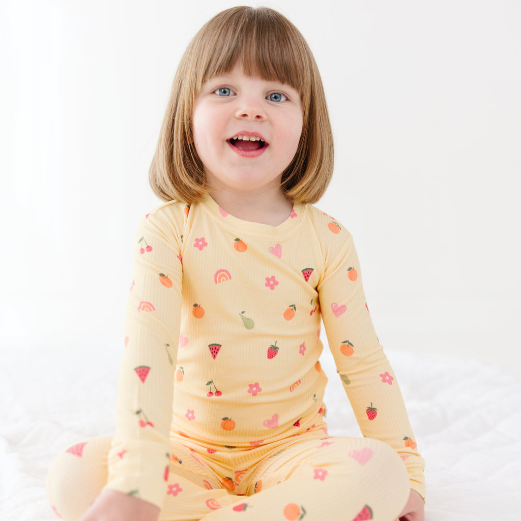 Child wearing a yellow pajama set with heart patterns on a white background