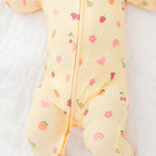 Baby wearing a yellow outfit with fruits patterns on a white background