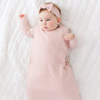 Baby wearing a pink and white striped outfit with a matching headband on a white background