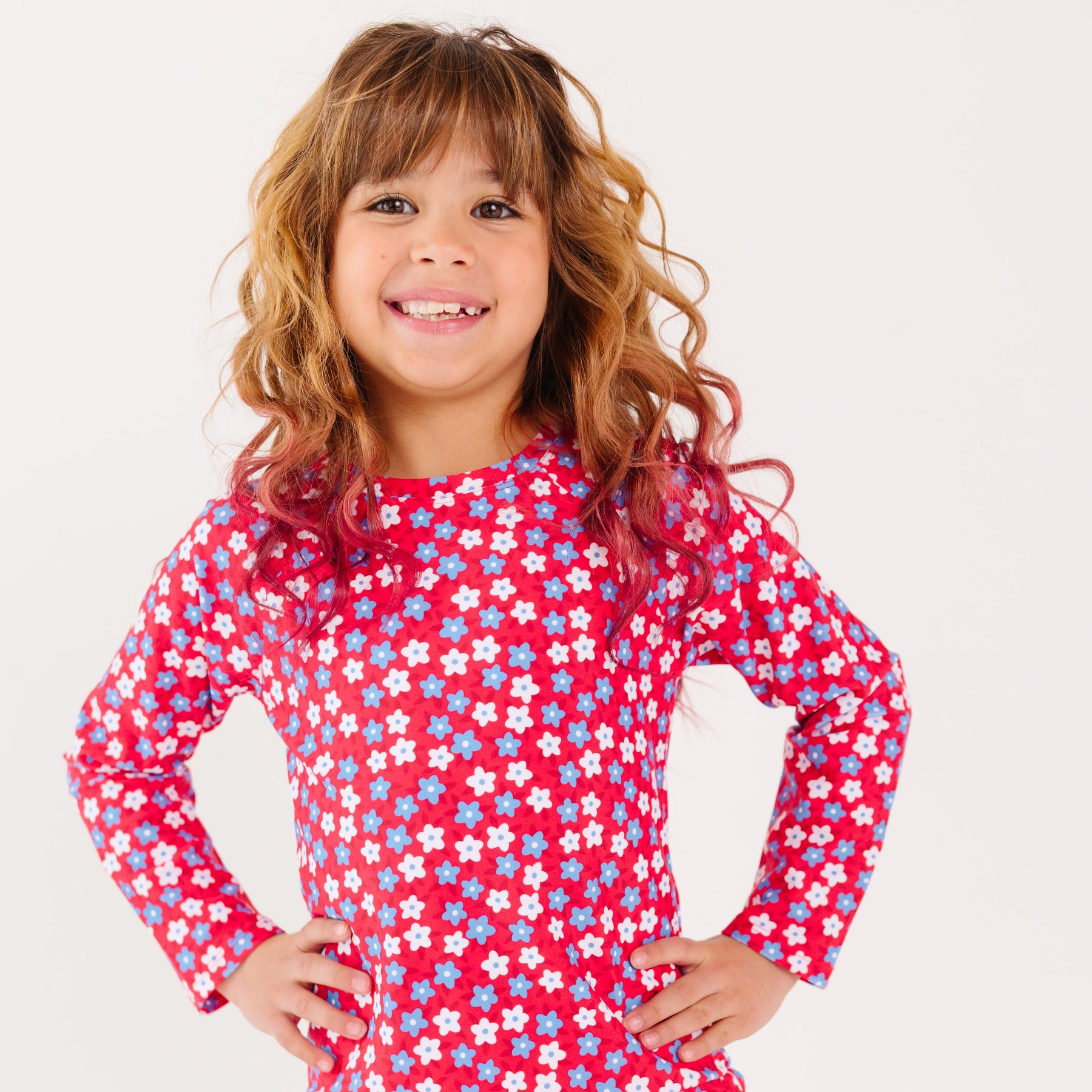 Young girl wearing a red floral swimsuit with long sleeves on a white background