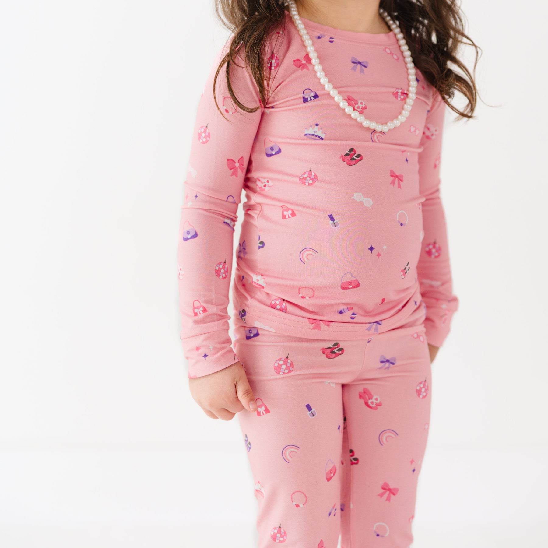Child wearing pink pajamas with a girly pattern on a white background