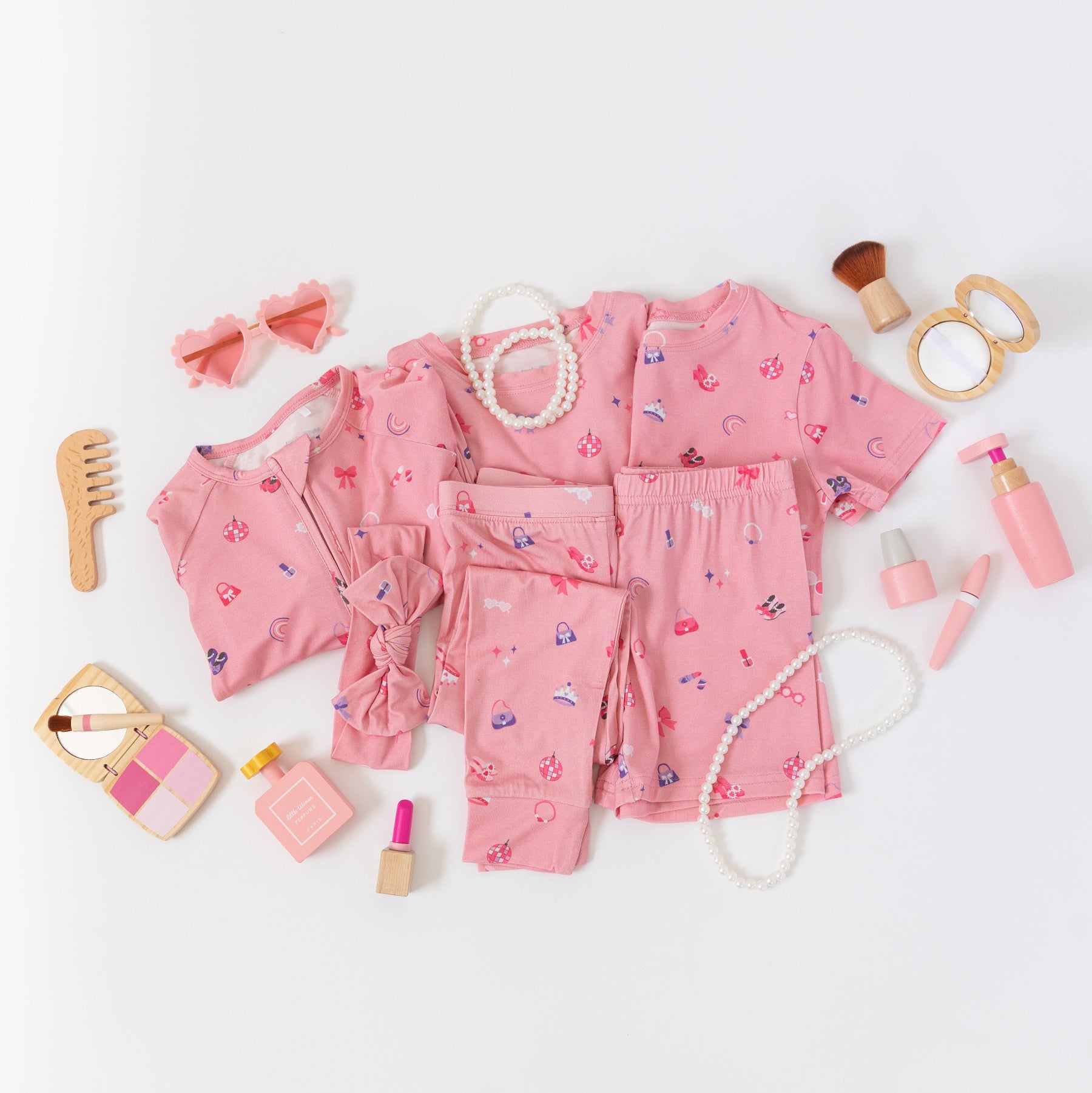 Collection of pink children's pajamas and accessories on a white background