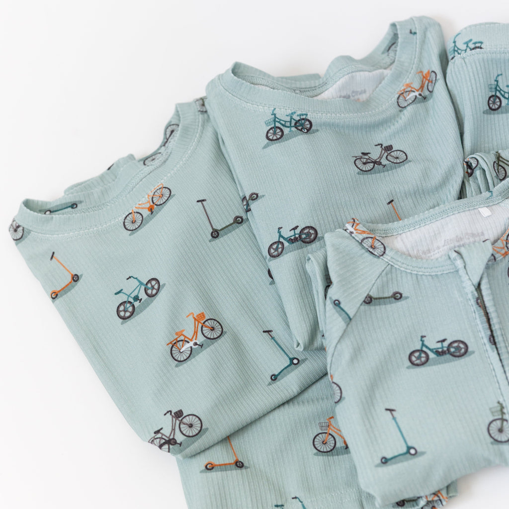 Light blue baby pajama sets with bicycle and scooter patterns on a white background