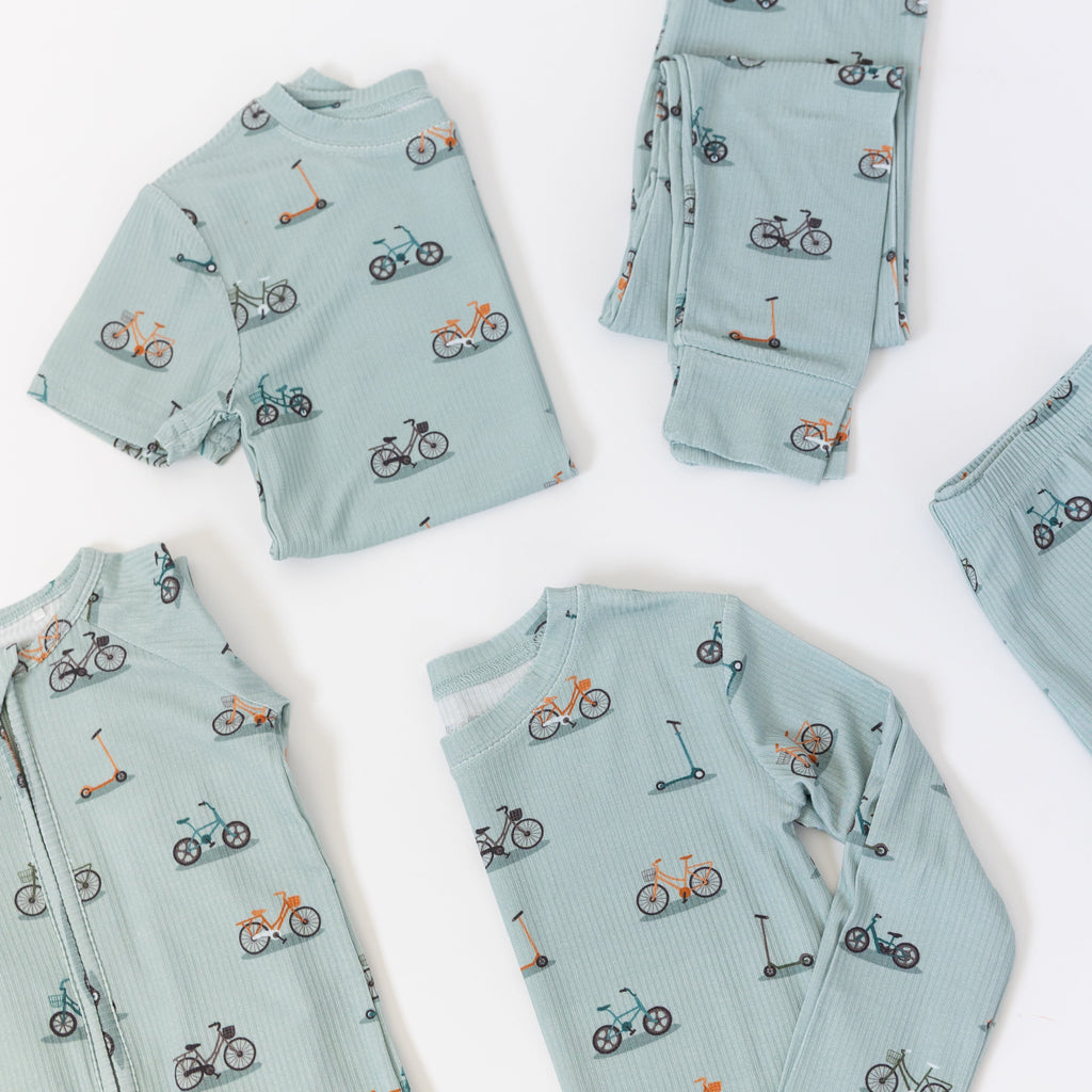 Light blue baby pajama sets with bicycle and scooter patterns on a white background