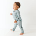 Child wearing a light blue onesie with vehicle patterns on a white background