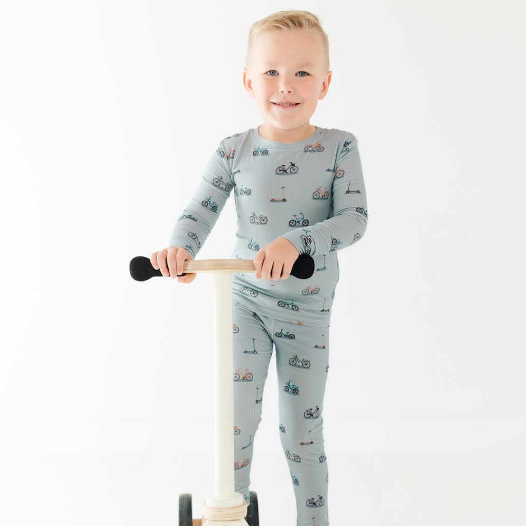 Child wearing a pajama set holding a scooter on a white background