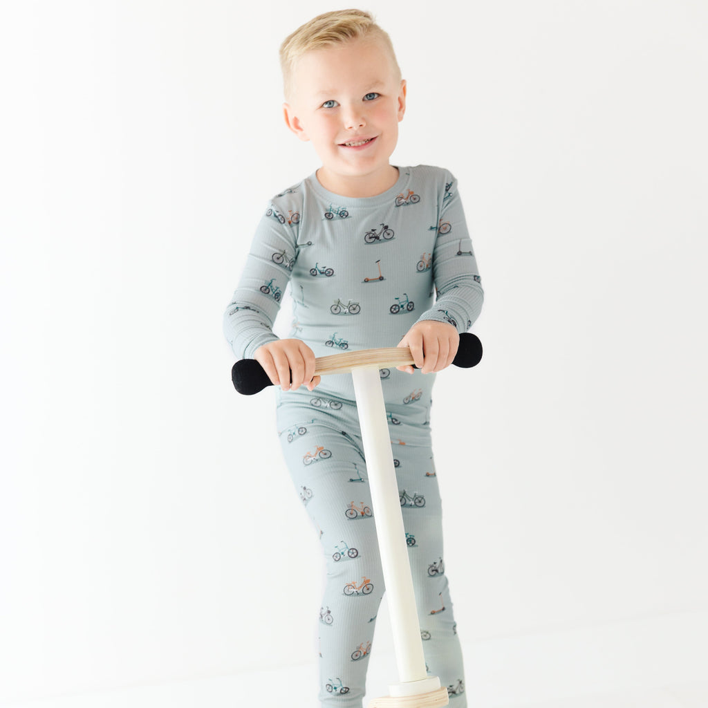 Child wearing a pajama set holding a scooter on a white background