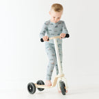 Child wearing a pajama set holding a scooter on a white background
