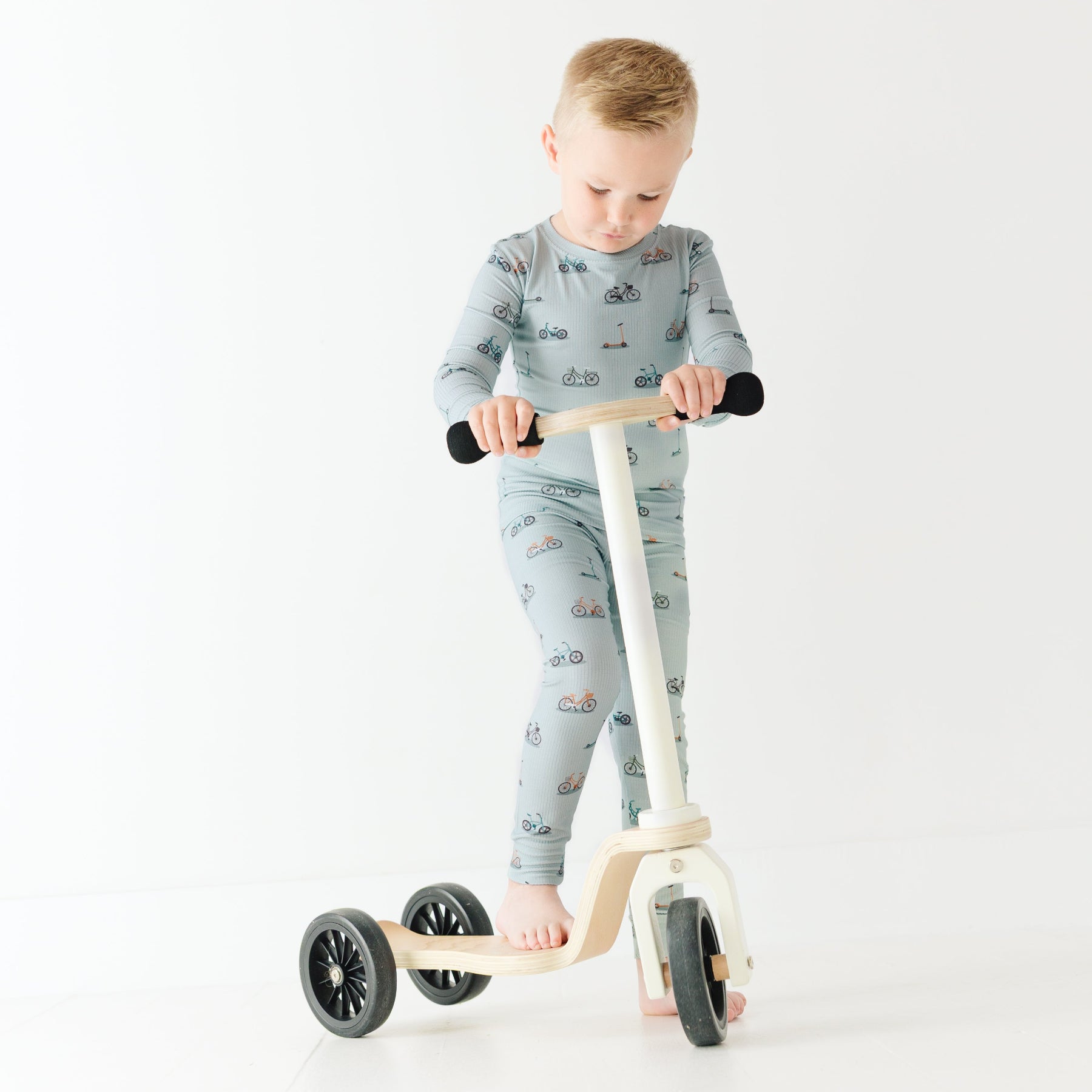 Child wearing a pajama set holding a scooter on a white background