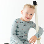Child wearing a light blue long-sleeve shirt with bicycle pattern, sitting on a scooter.