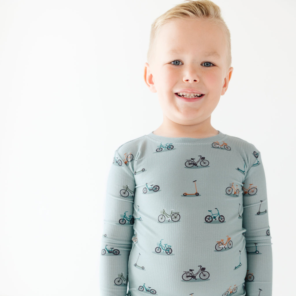 Child wearing a light blue long-sleeve shirt with bicycle pattern on a white background