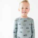Child wearing a light blue long-sleeve shirt with bicycle pattern on a white background
