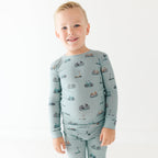 Child wearing a light blue long-sleeve shirt with vehicle patterns on a white background