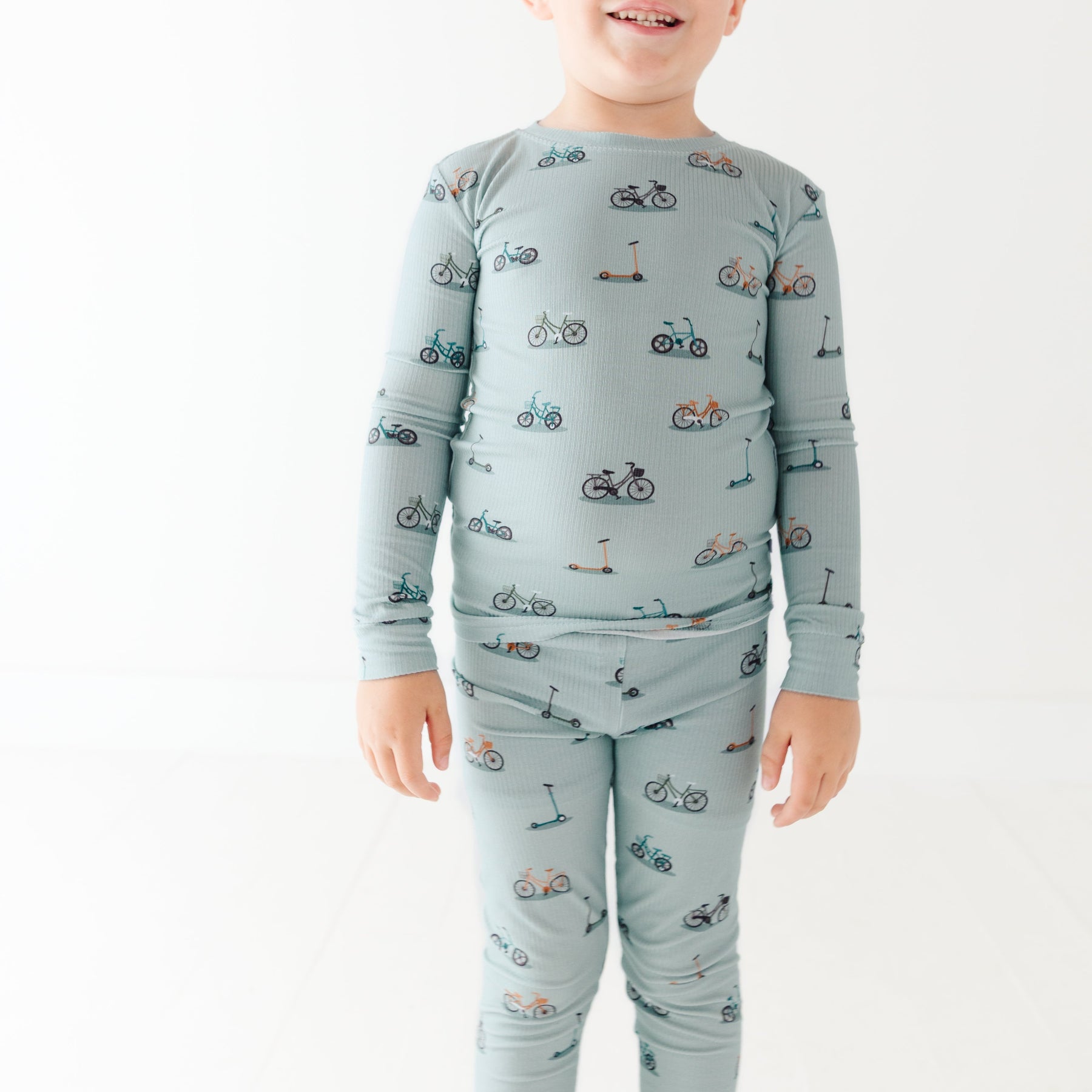 Child wearing a light blue pajama set with vehicle pattern on a white background