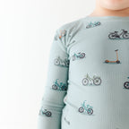 Close up shot of a child wearing a light blue long-sleeve shirt with bicycle pattern on a white background