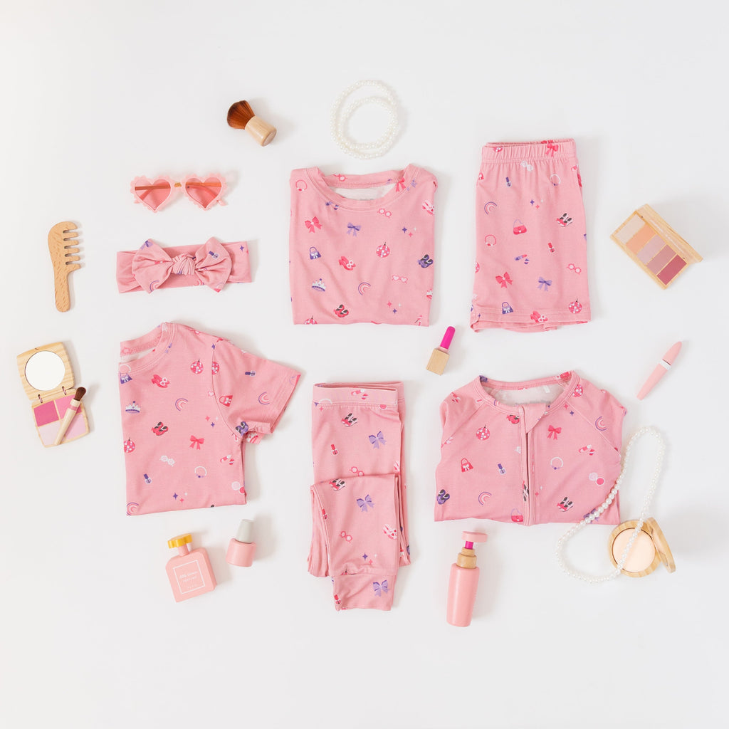 Collection of pink children's pajamas and accessories on a white background