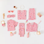 Collection of pink children's pajamas and accessories on a white background