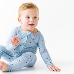 Child wearing a light blue onesie with stars and flag patterns on a white background