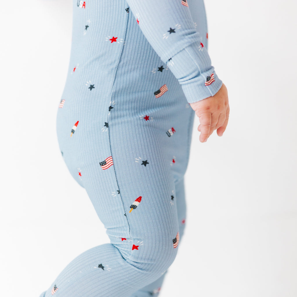 Close up shot of a baby onesie with small American flags and star patterns on a white background.