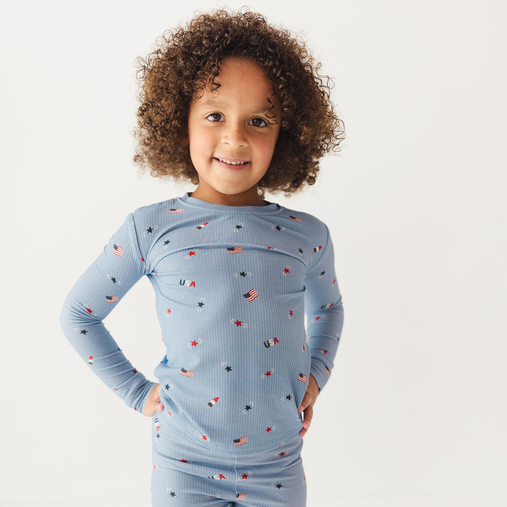 Child wearing a blue pajama set with stars and flag patterns on a white background