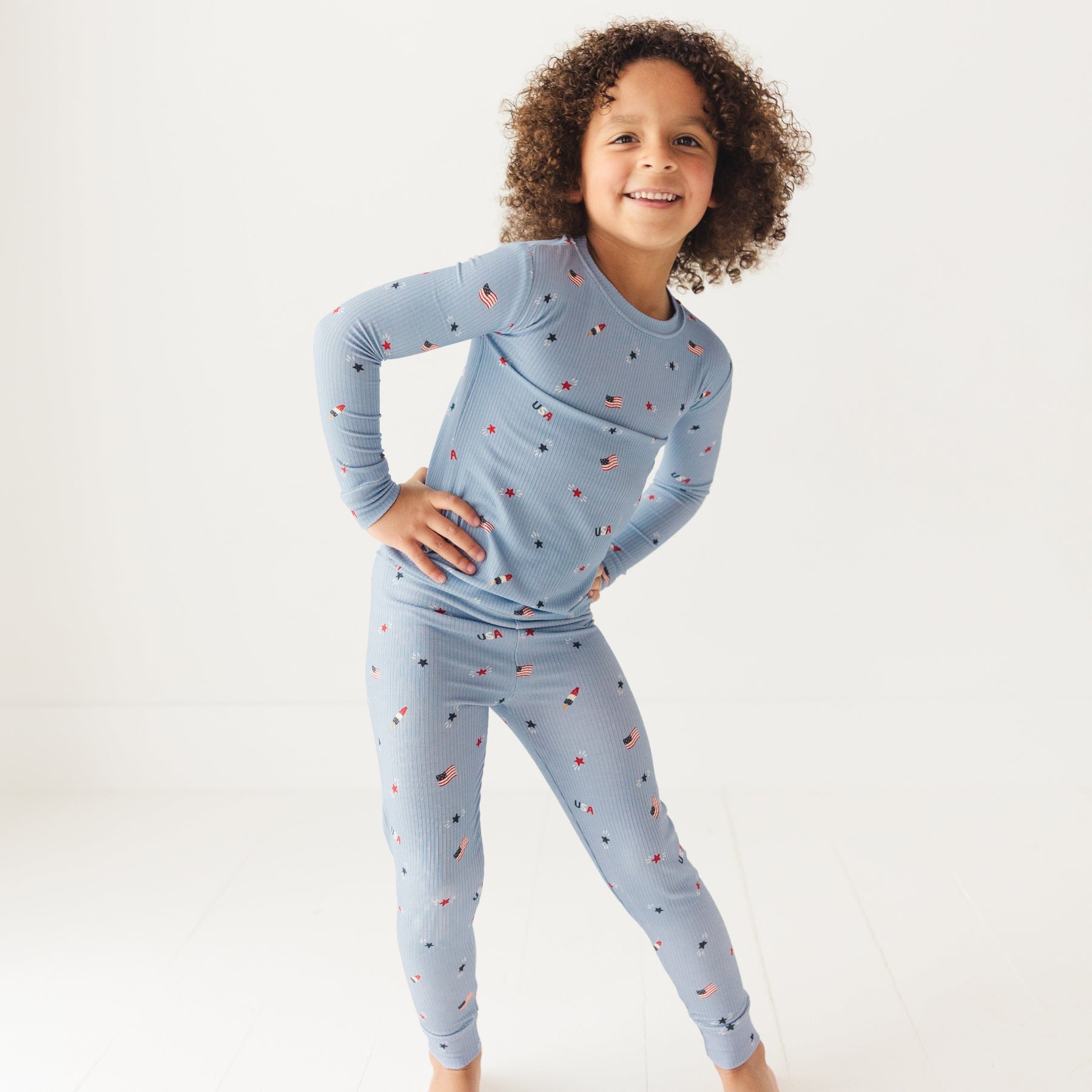 Child wearing a blue pajama set with stars and flag patterns on a white background