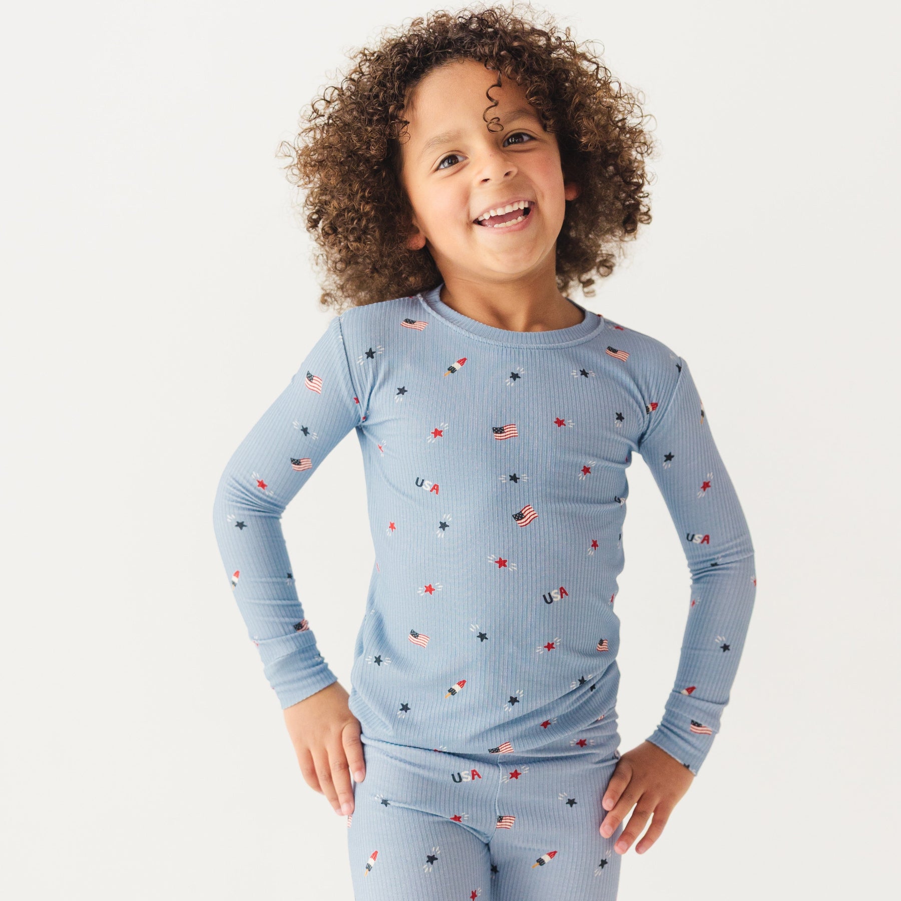 Child wearing a blue pajama set with stars and flag patterns on a white background