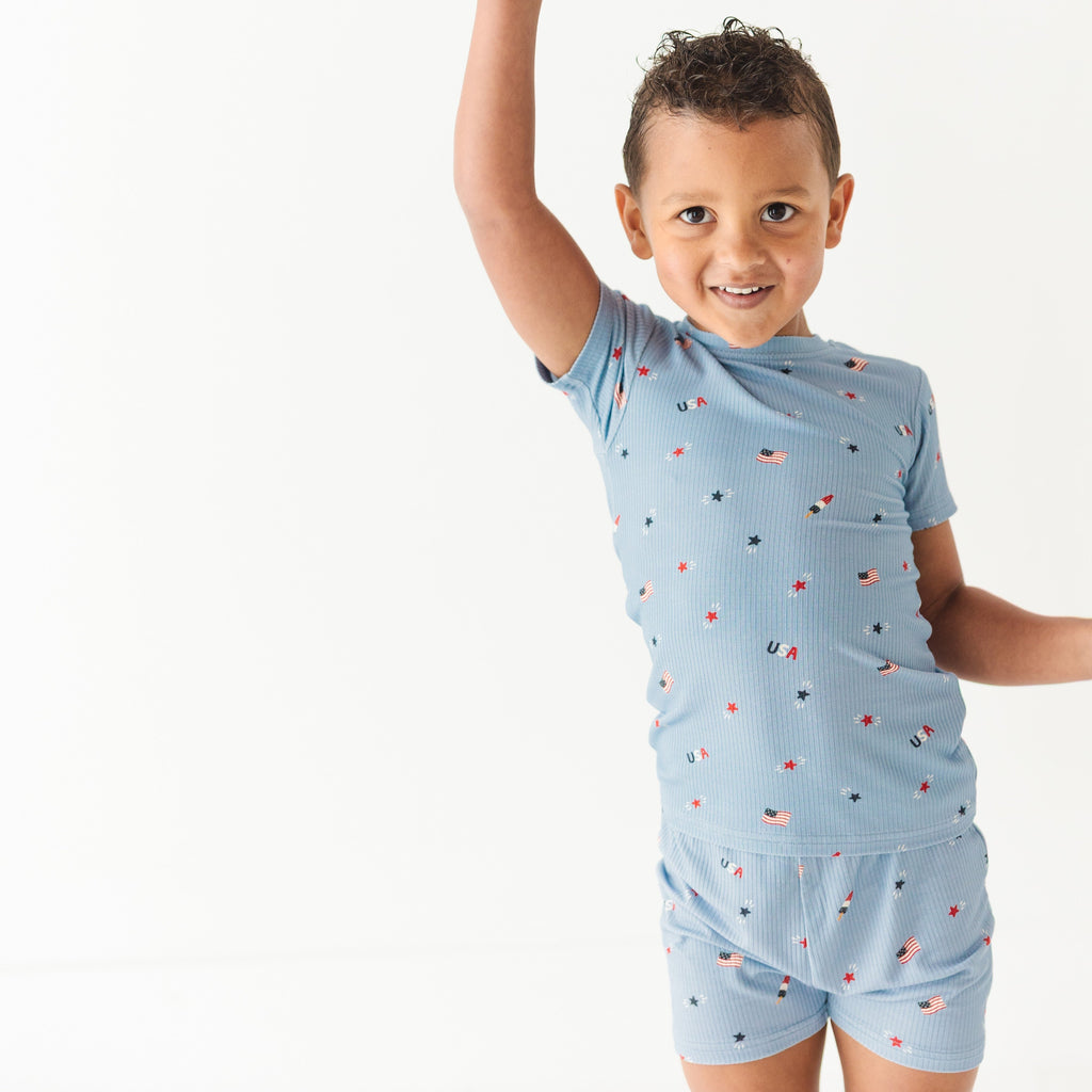 Child wearing a light blue outfit with small American flag pattern on a white background