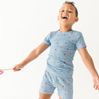 Child wearing a light blue outfit with small American flag pattern on a white background