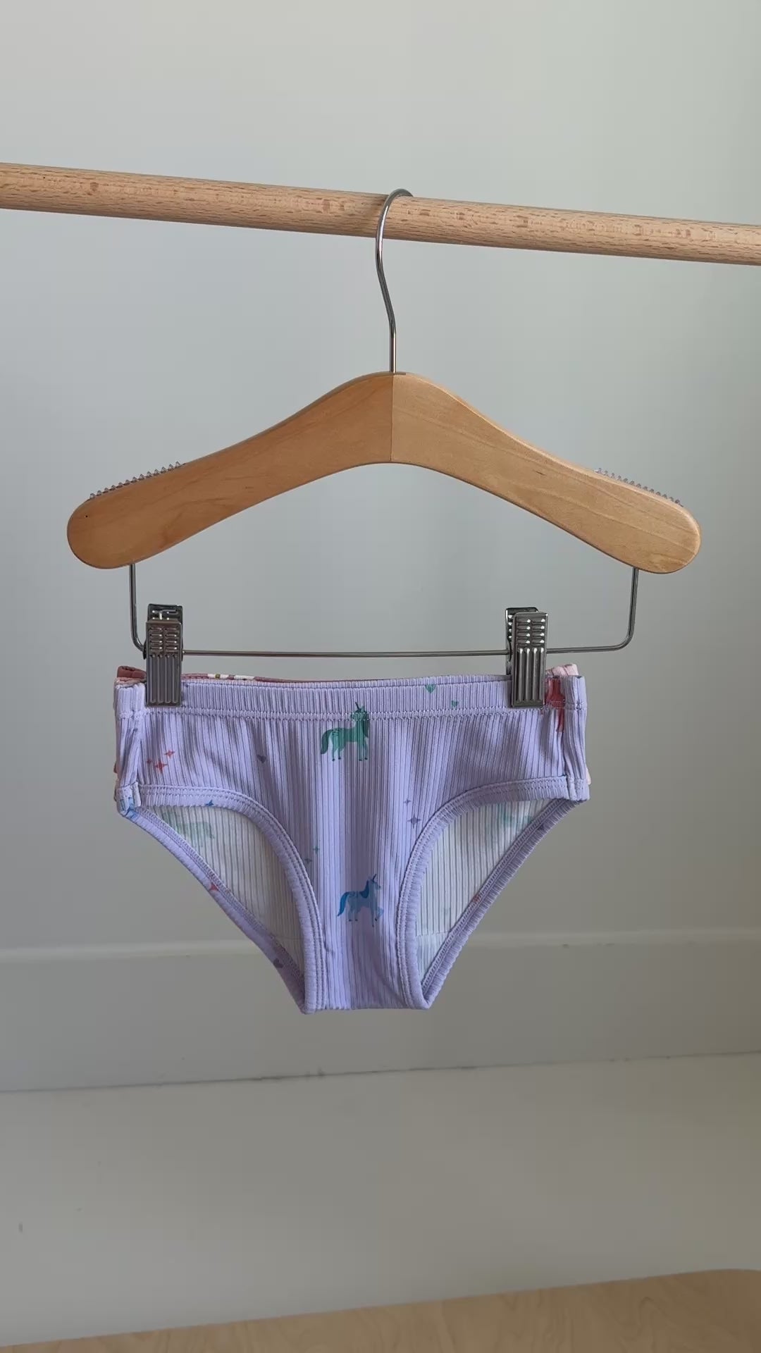 Video of a set of three children's underwear with different girly patterns hanging on a rack