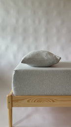 Video of a bed with wooden frame and light gray mattress and pillow 