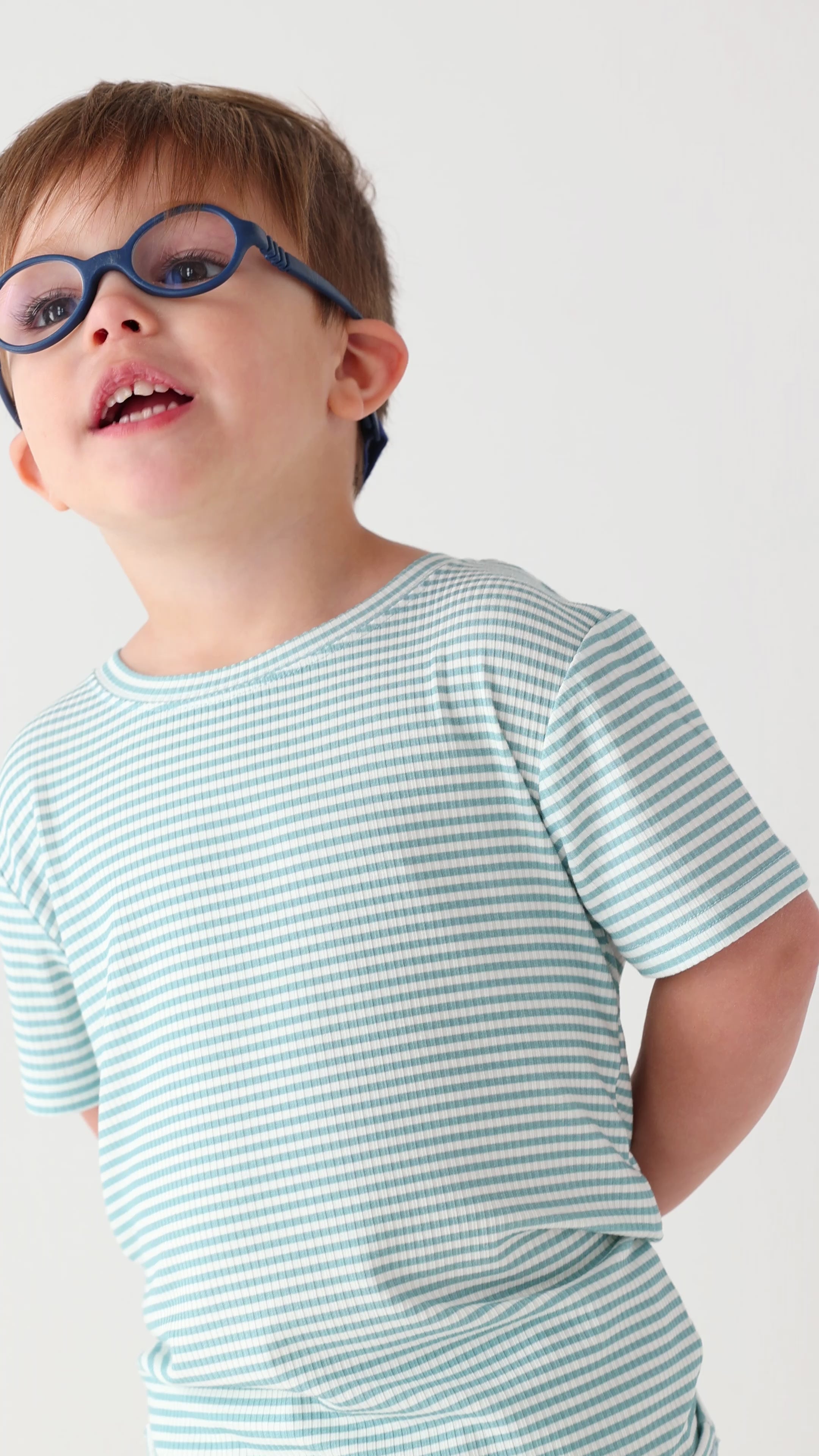 Child wearing a light blue striped shirt and shorts set on a white background