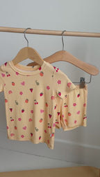 Yellow shorts pajama set with fruit and heart patterns hanging on a rack