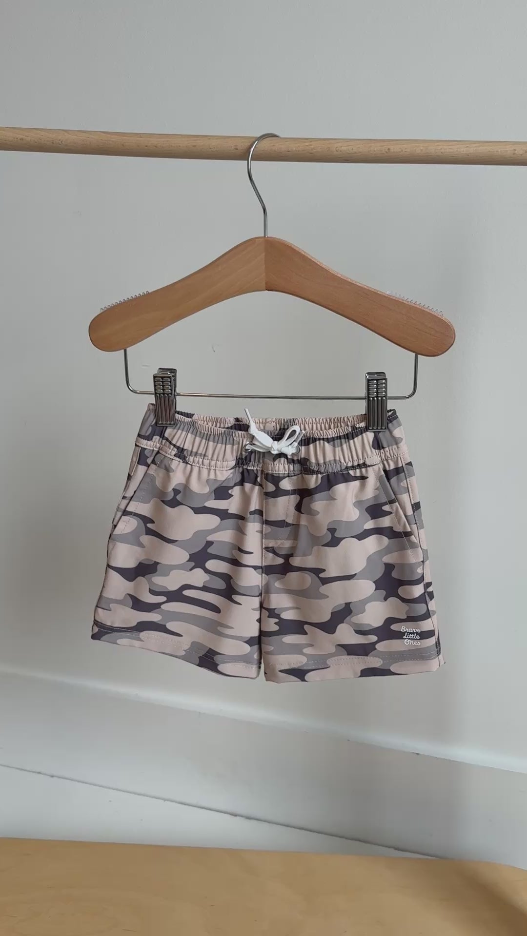 Camouflage shorts with a brand logo hanging on a rack