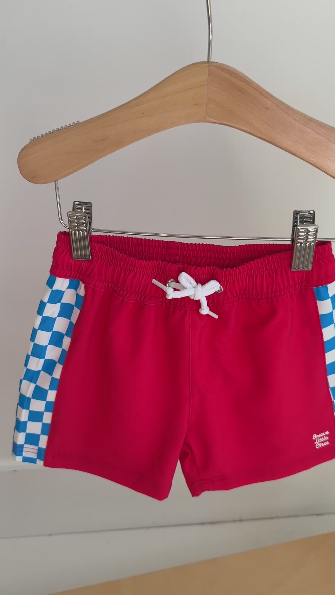 Red shorts with blue and white checkered sides hanging on a rack