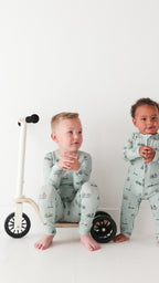 Video of two children wearing matching pajamas standing next to a small bike on a white background