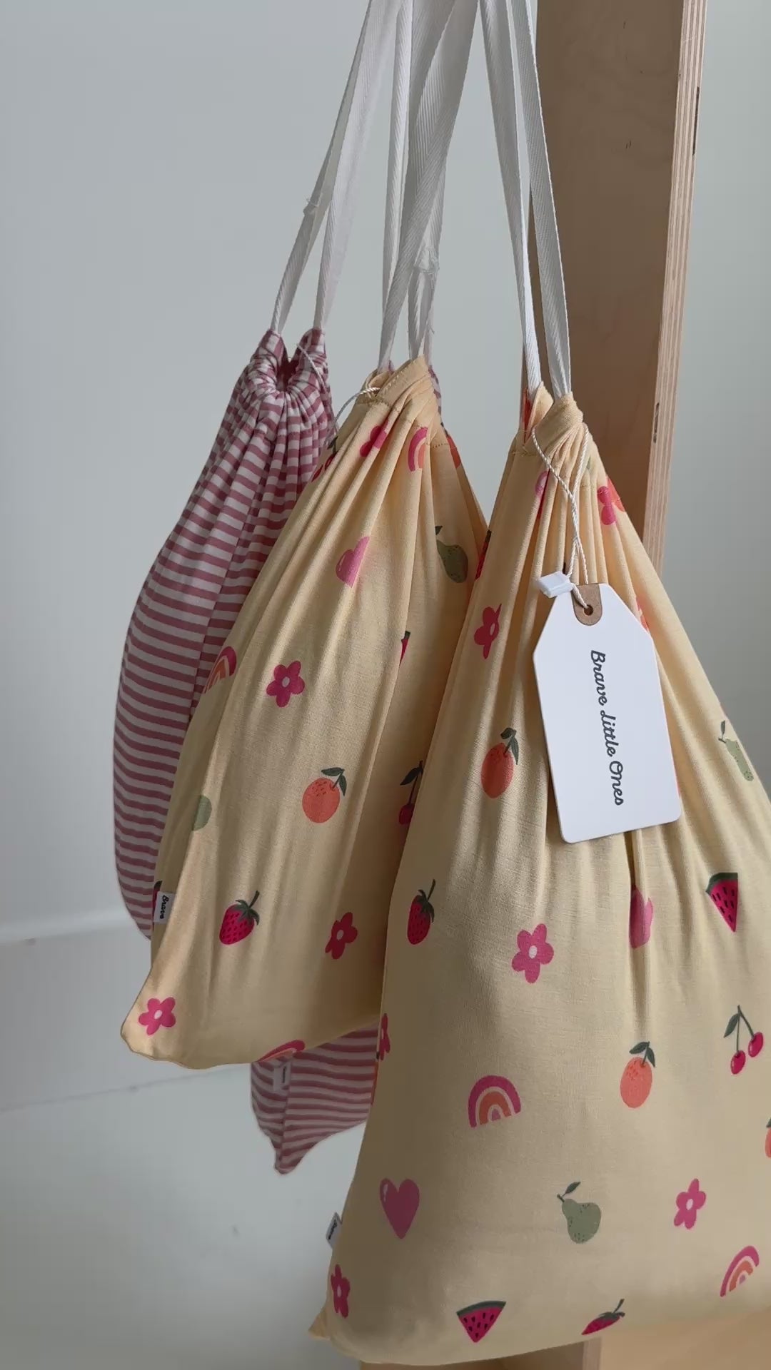 Pink striped sheets and fruity-patterned sheets in bags hanging on a rack