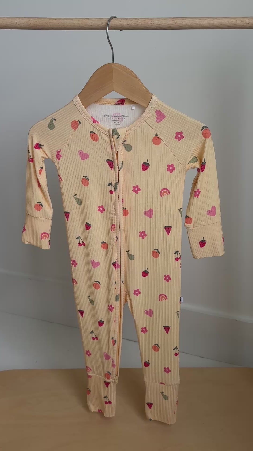 Children's  yellow onesie with colorful pattern hanging on a rack