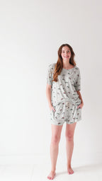 Woman wearing a light gray pajama set with vehicle patterns on a white background