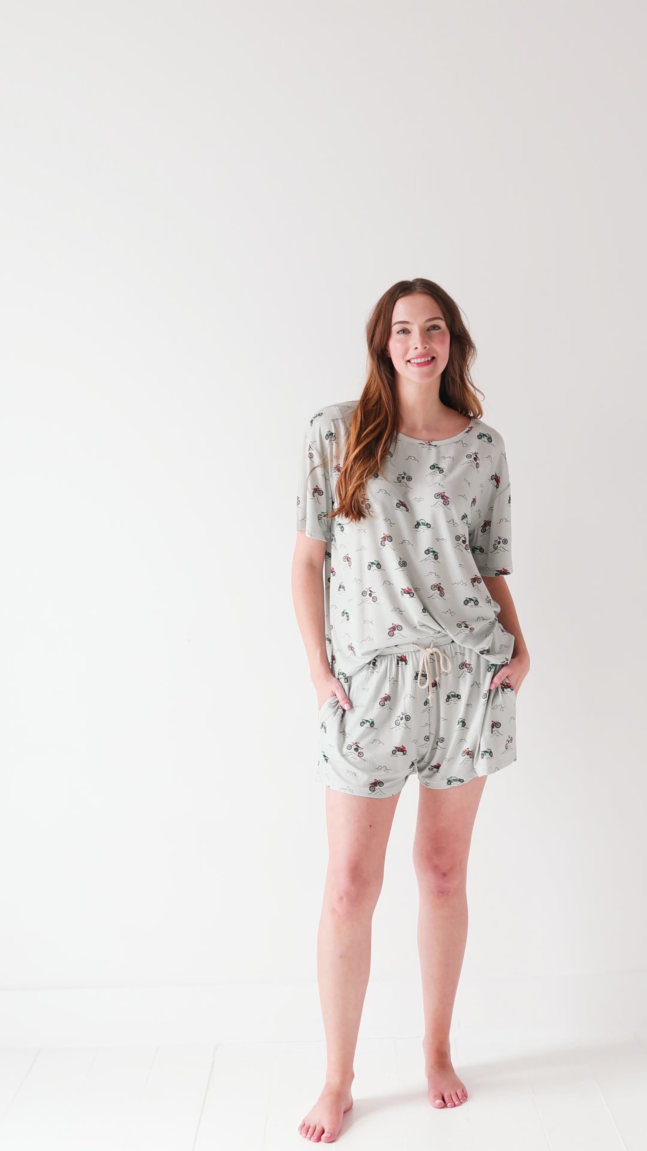 Woman wearing a light gray pajama set with vehicle patterns on a white background