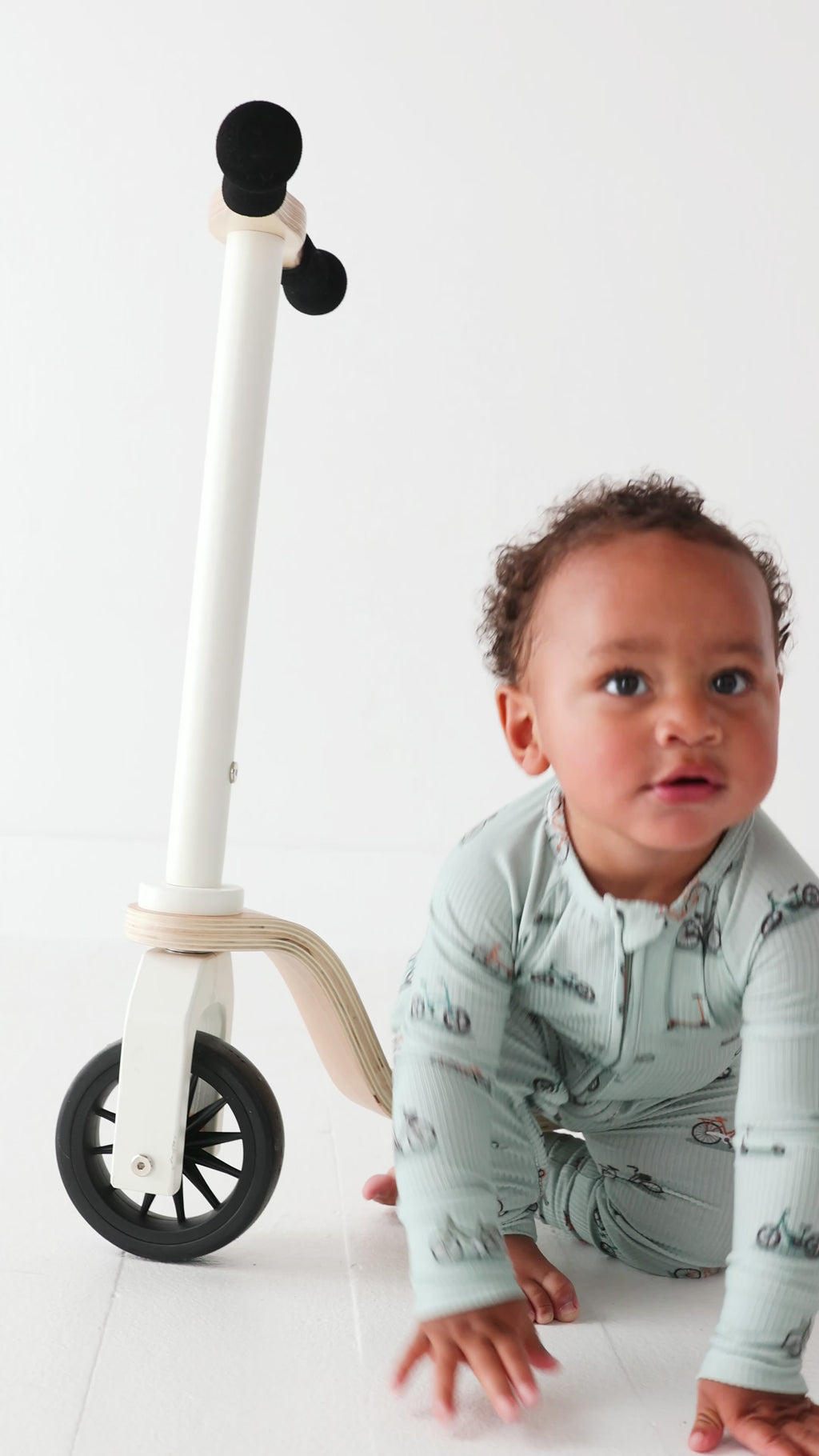 Video of a child using a scooter wearing a onesie with bicycles and scooters print