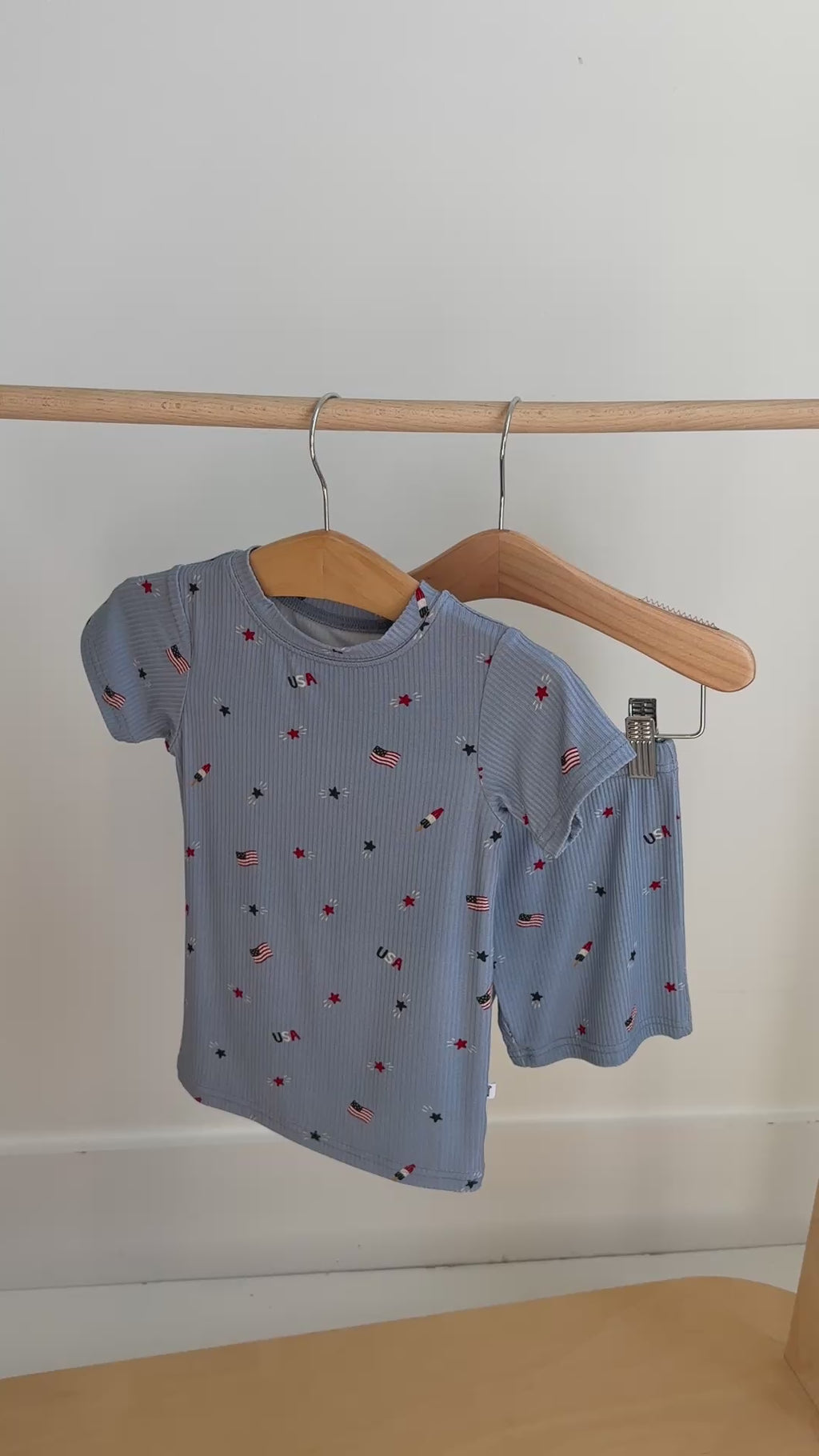 Children's shorts pajama set with American flag pattern hanging on a rack