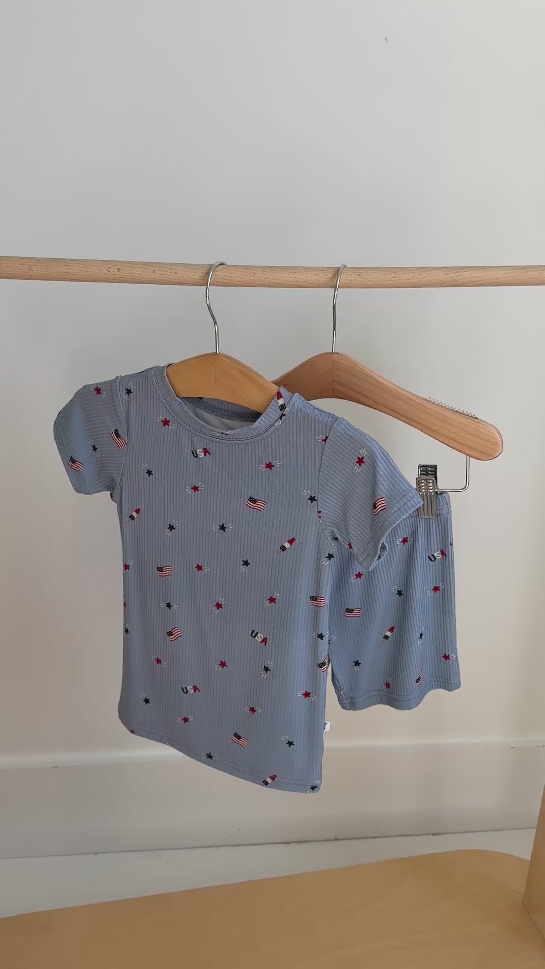 Children's shorts pajama set with American flag pattern hanging on a rack